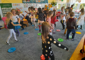 Dzieci tańczą wśród kolorowych kropek/klocków.